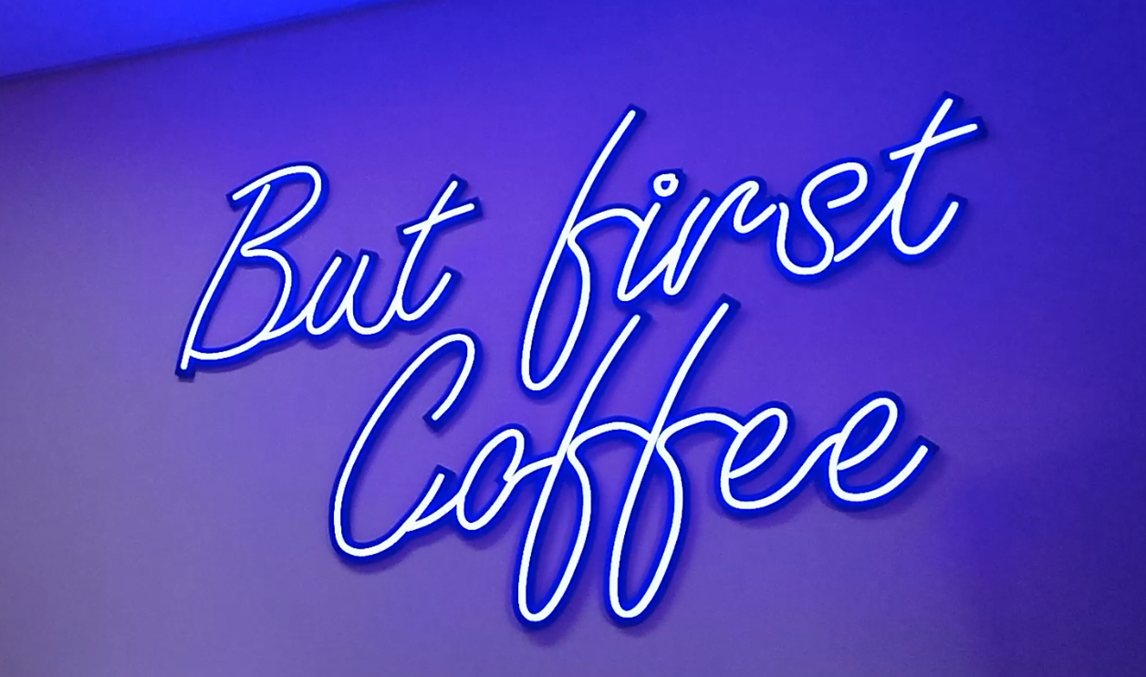 Neon purple sign saying 'but first coffee'